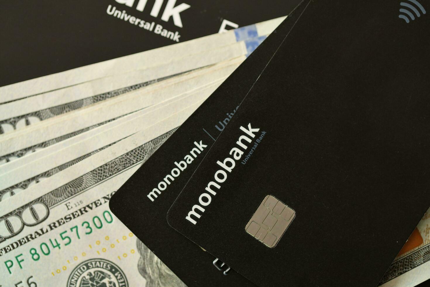 KYIV, UKRAINE - JULY 7, 2023 Monobank banking plastic cards with money on table photo