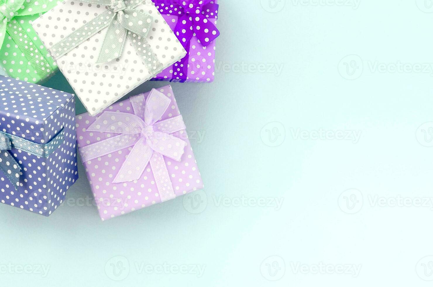 Pile of a small colored gift boxes with ribbons lies on a violet background. Minimalism flat lay top view photo