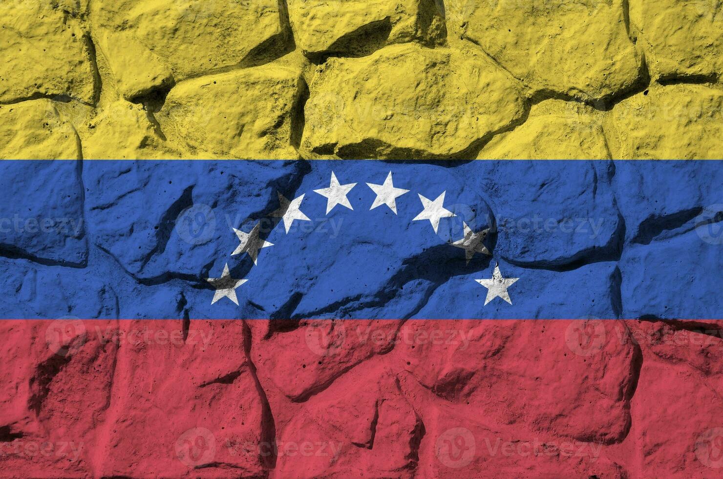 Venezuela flag depicted in paint colors on old stone wall closeup. Textured banner on rock wall background photo