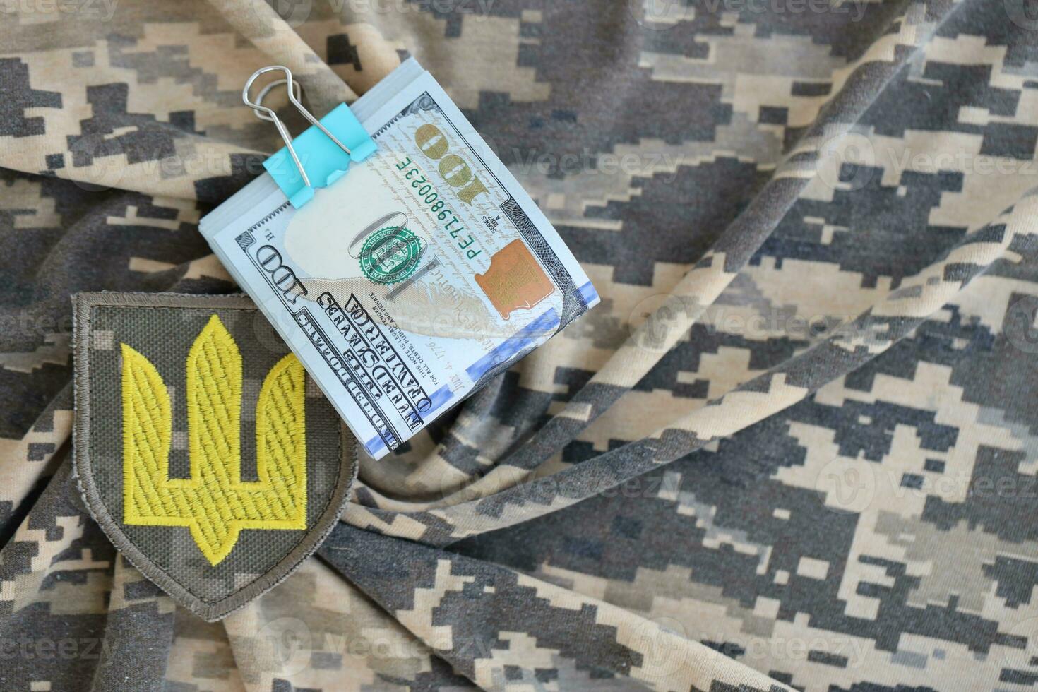 Ukrainian army symbol and bunch of dollar bills on military uniform. Payments to soldiers of the Ukrainian army from United States, salaries to the military. War support photo