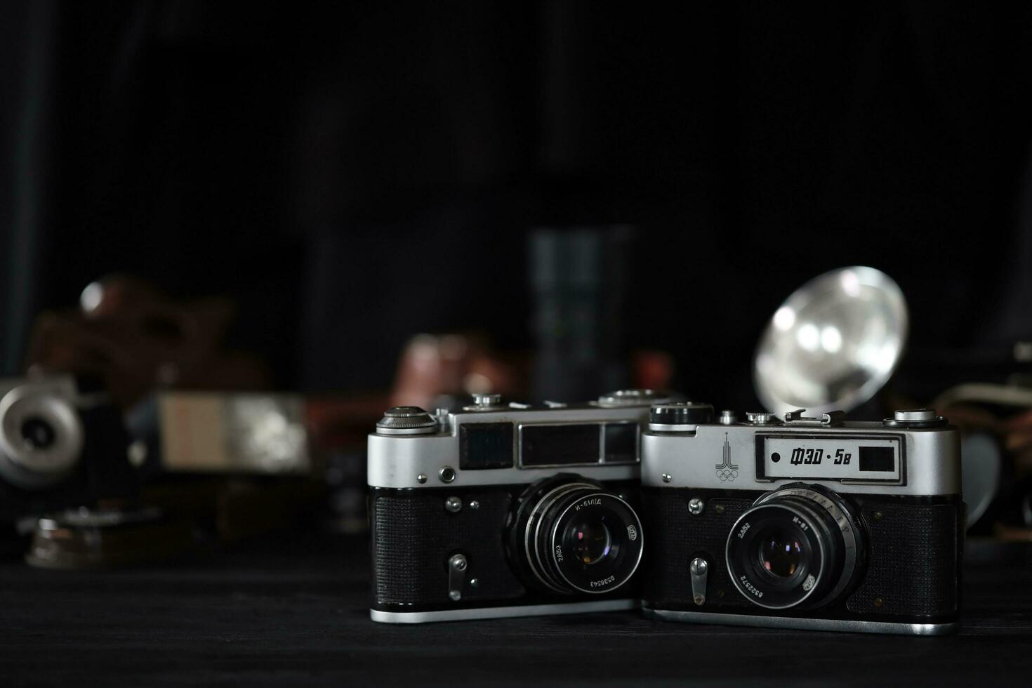 KHARKOV, UKRAINE - APRIL 27, 2021 Fed 4 and 5b Film photo camera and another old retro photo equipment on black wooden table in photographer darkroom. Photographic gear from soviet union