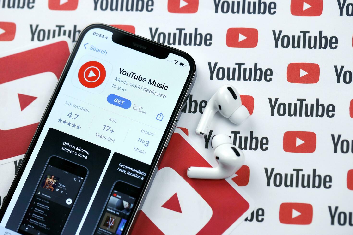 KHARKOV, UKRAINE - MARCH 5, 2021 Youtube music icon and application from App store on iPhone 12 pro display screen with airpods pro on white table photo