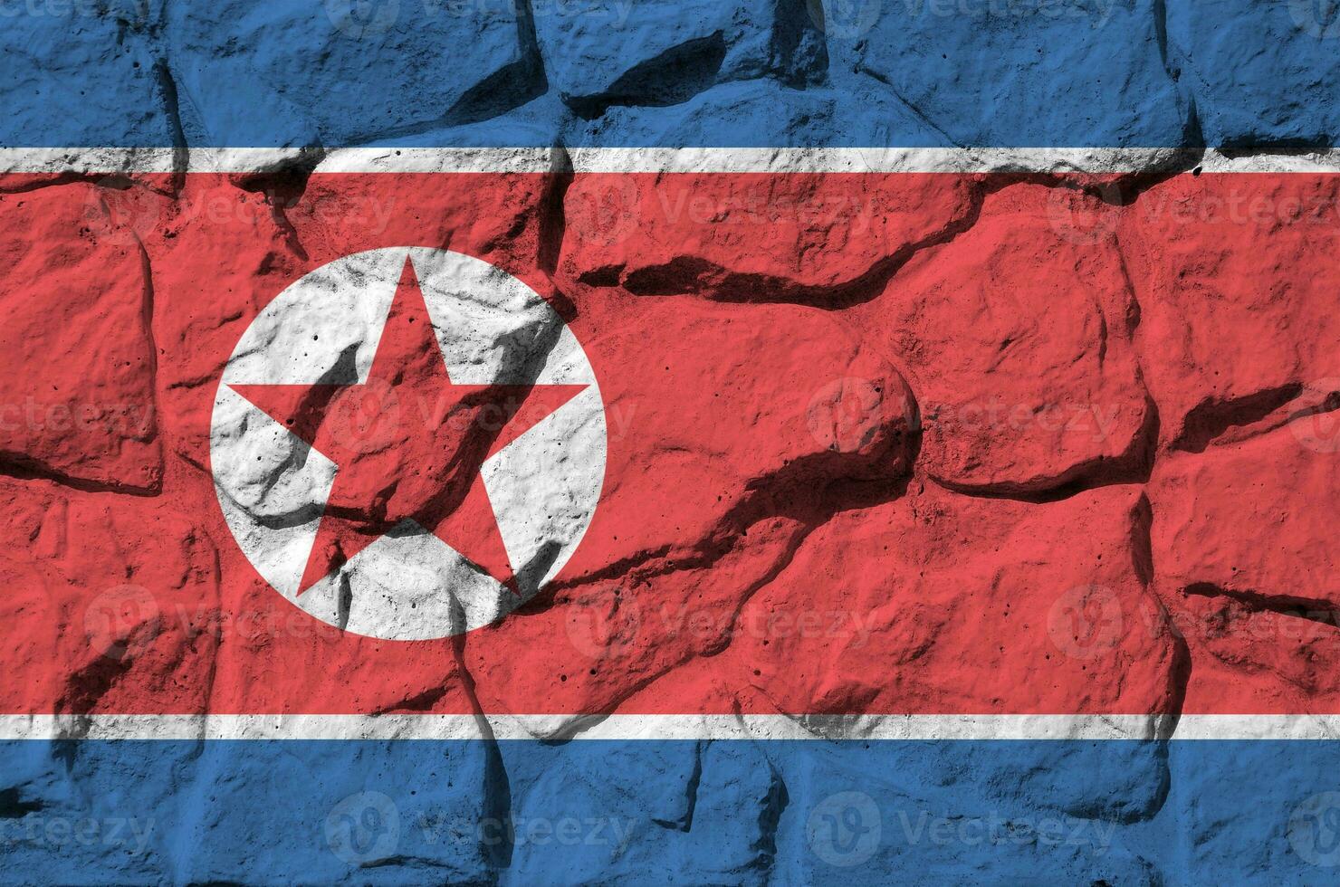 North Korea flag depicted in paint colors on old stone wall closeup. Textured banner on rock wall background photo