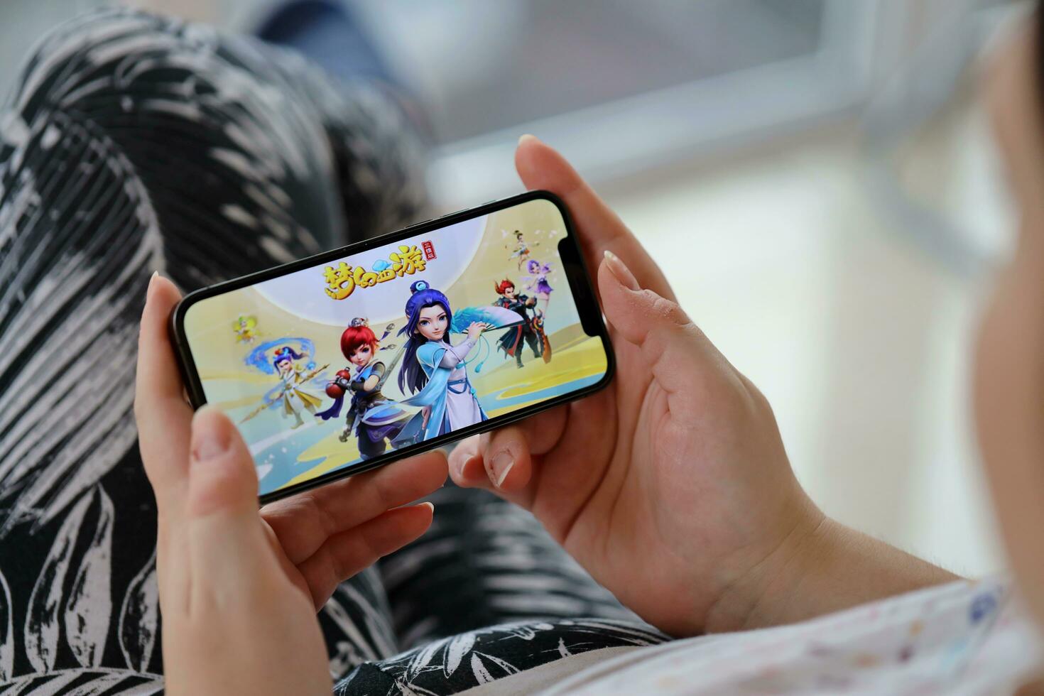 Fantasy Westward Journey mobile iOS game on iPhone 15 smartphone screen in female hands during mobile gameplay photo
