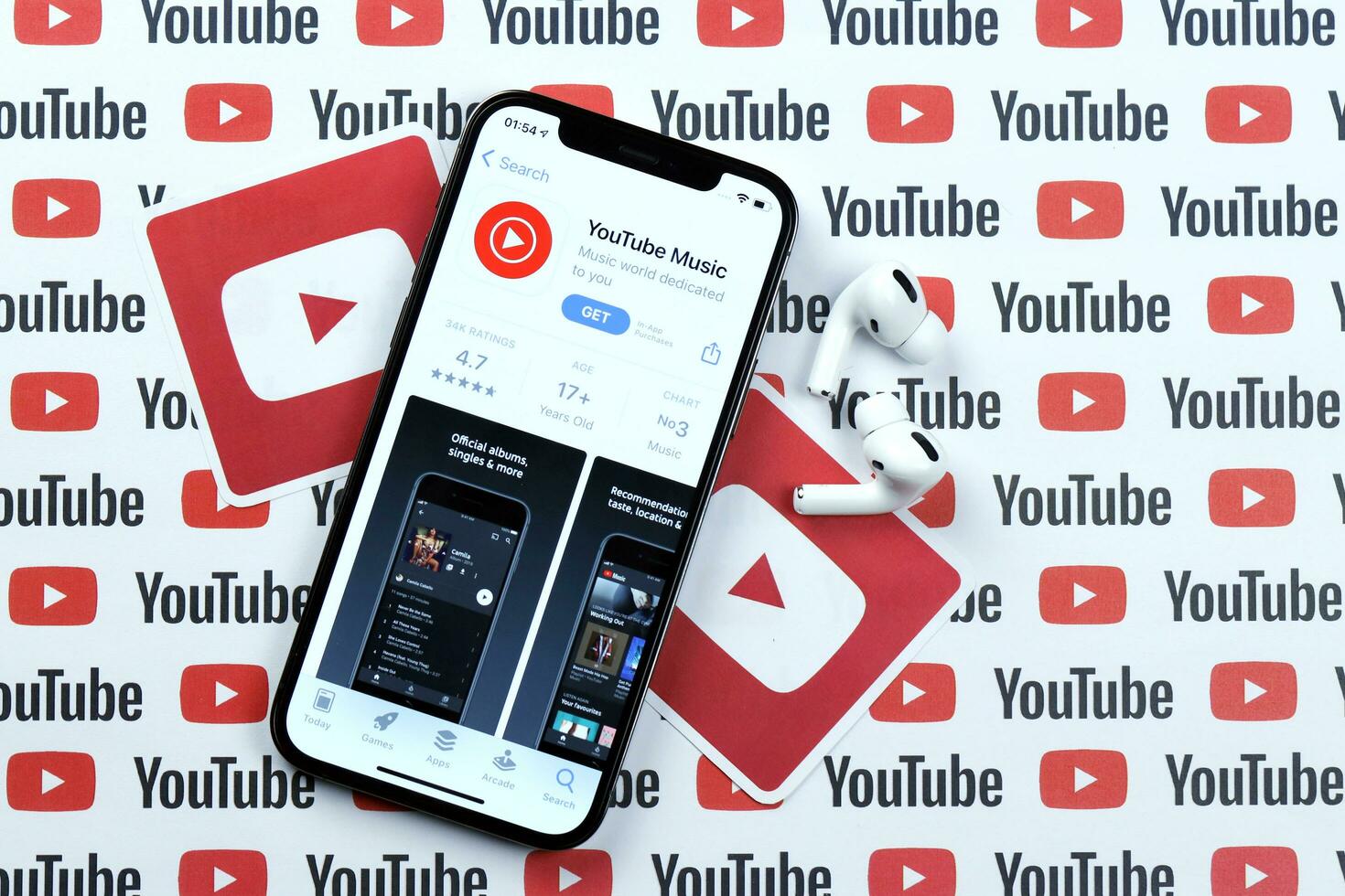 KHARKOV, UKRAINE - MARCH 5, 2021 Youtube music icon and application from App store on iPhone 12 pro display screen with airpods pro on white table photo
