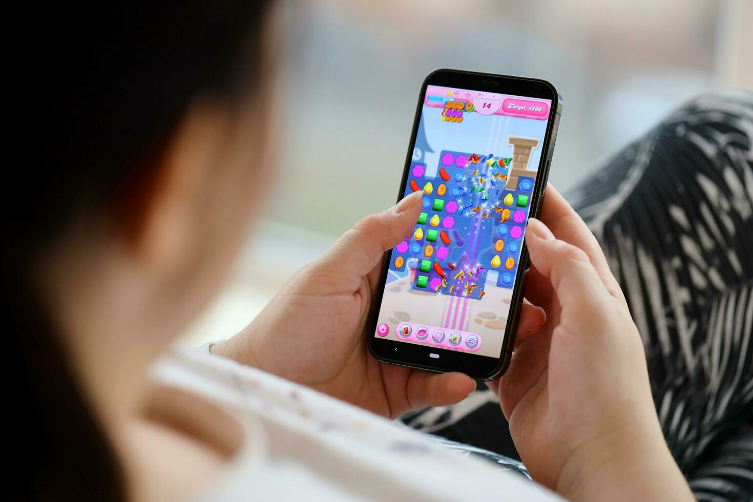 Candy Crush Saga mobile iOS game on iPhone 15 smartphone screen in female hands during mobile gameplay photo