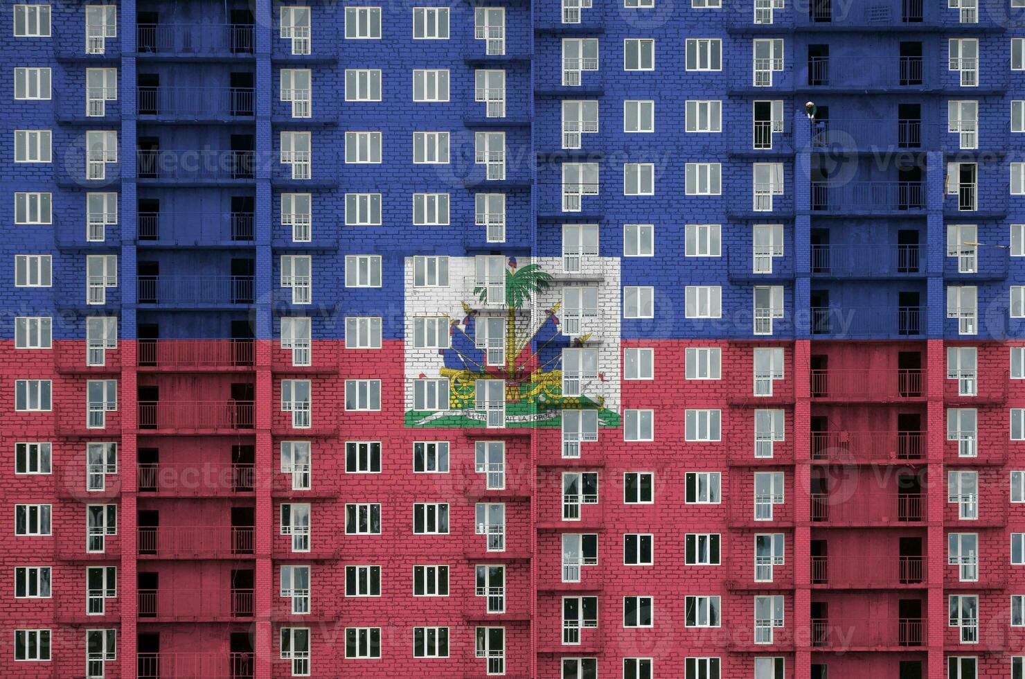 Haiti flag depicted in paint colors on multi-storey residental building under construction. Textured banner on brick wall background photo