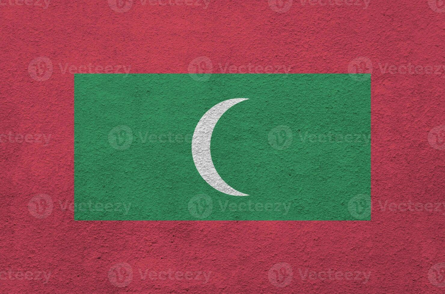 Maldives flag depicted in bright paint colors on old relief plastering wall. Textured banner on rough background photo