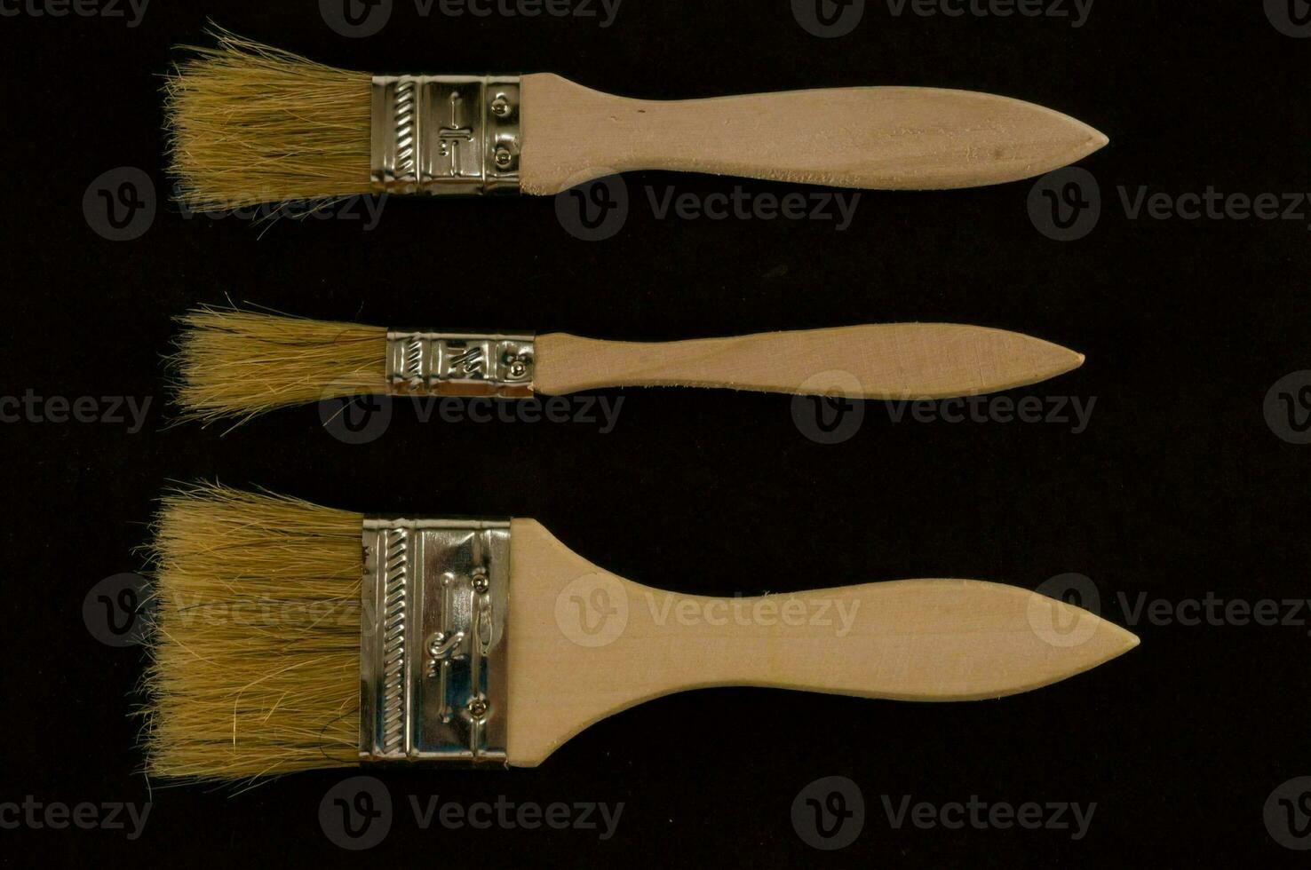 three brushes with wooden handles and bristles photo