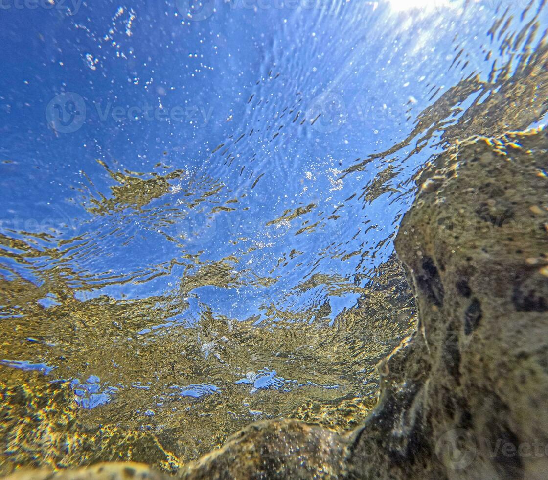 Underwater image of a rocky coastline with turquoise water towards the surface photo