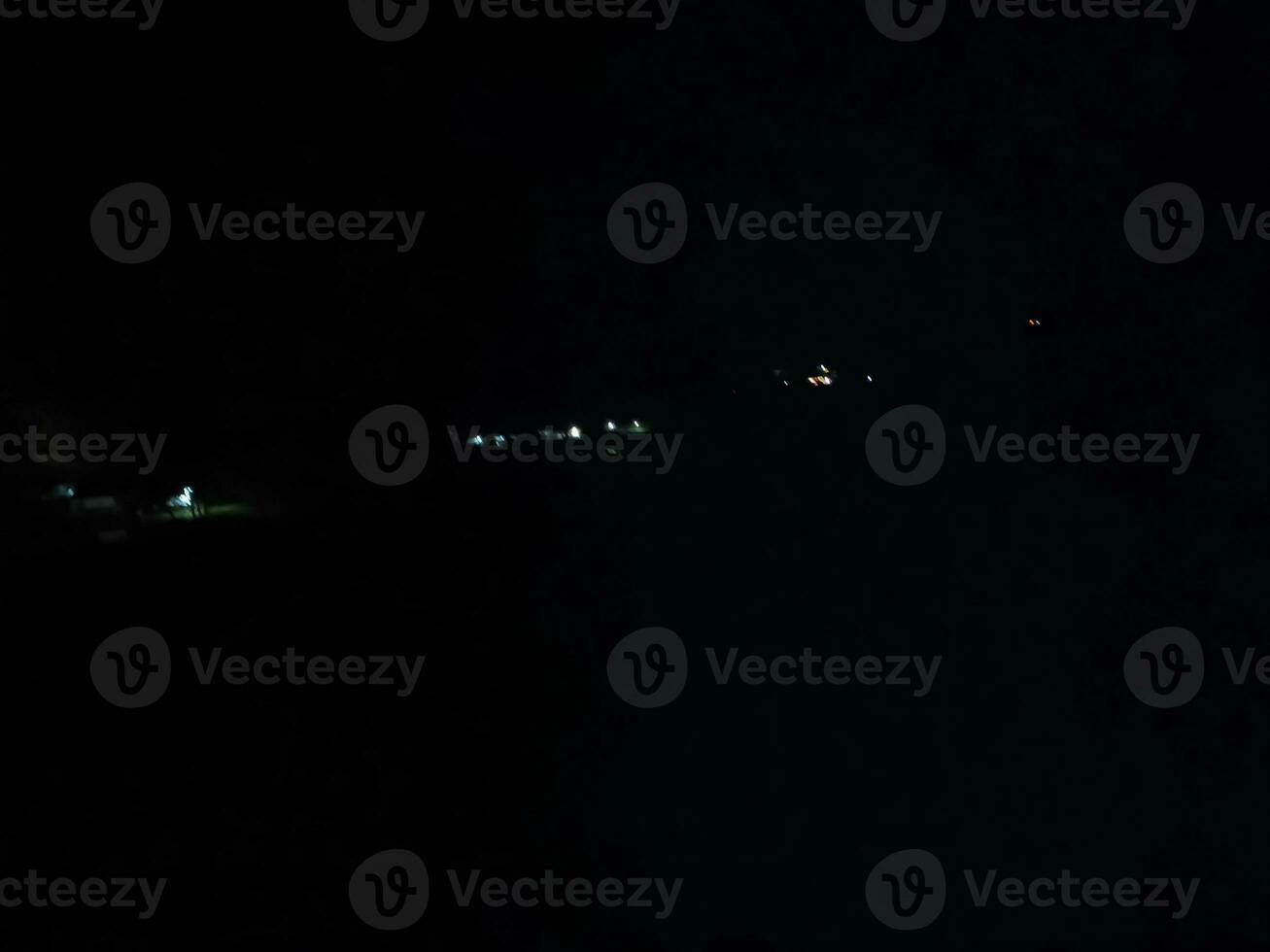 fir trees on meadow between hillsides with conifer forest in fog under the blue sky at night. spooky countryside scenery in full moon light photo