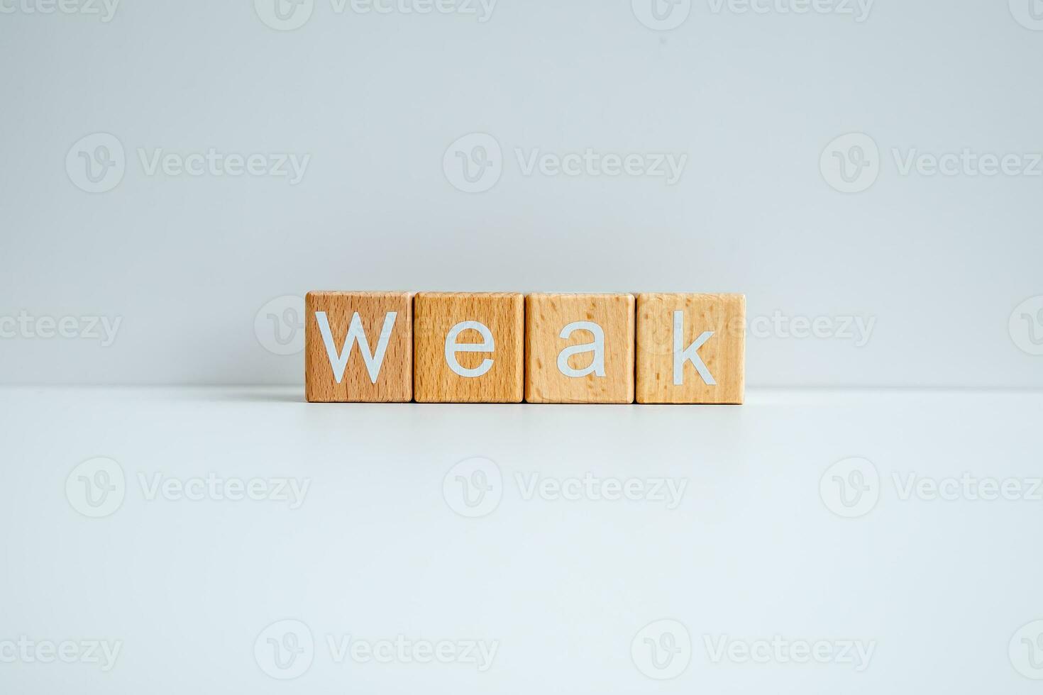 Wooden blocks form the text Weak against a white background. photo