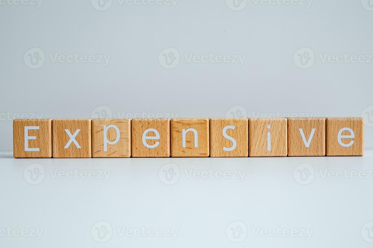 Wooden blocks form the text Expensive against a white background. photo