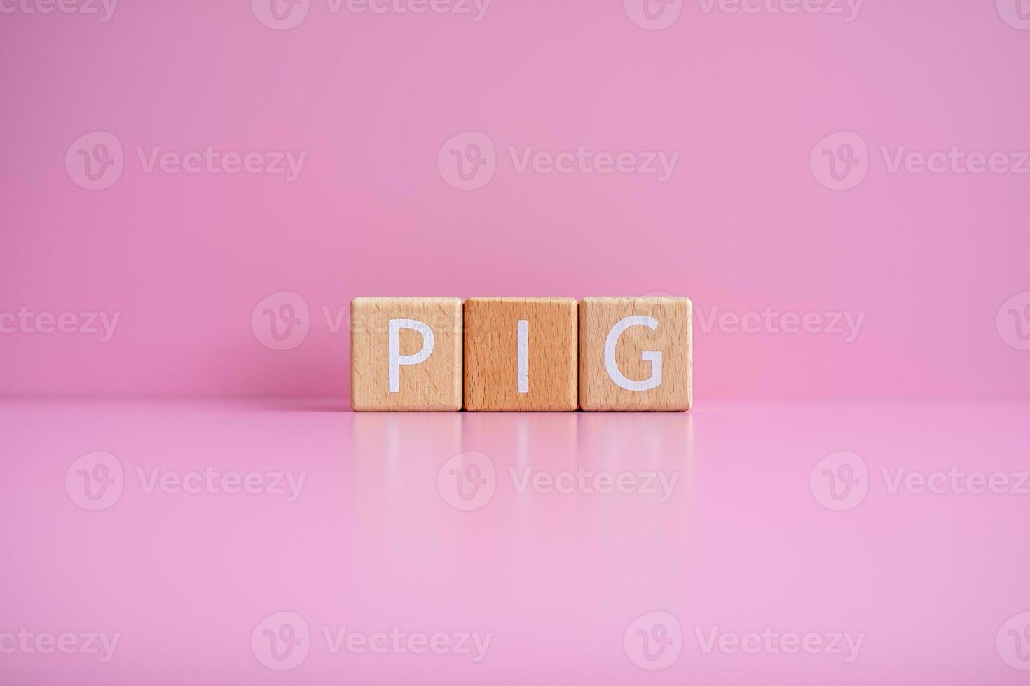 Wooden blocks form the text PIG against a pink background. photo