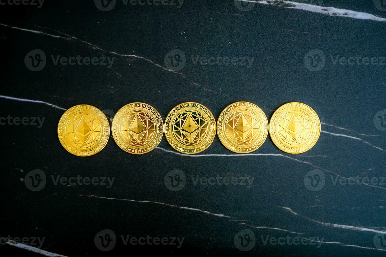 5 Ethereum coins ETH lined up on a black marble background. photo