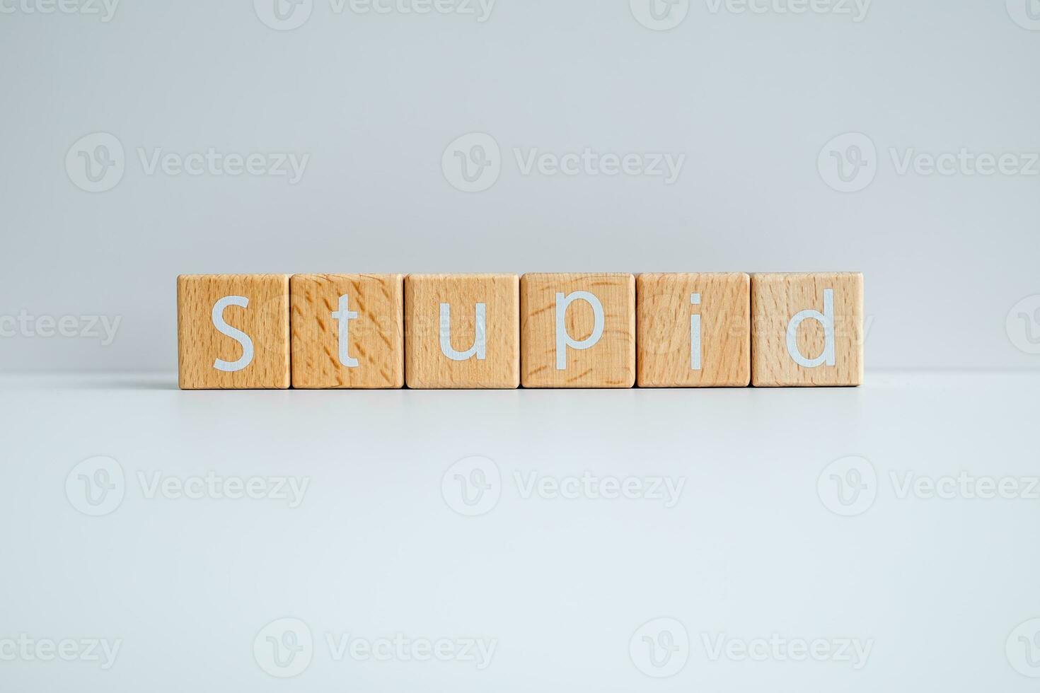 Wooden blocks form the text Stupid against a white background. photo