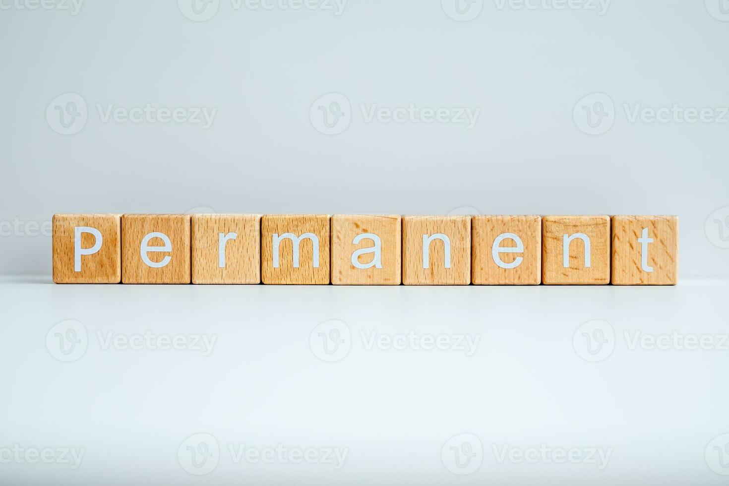 Wooden blocks form the text Permanent against a white background. photo