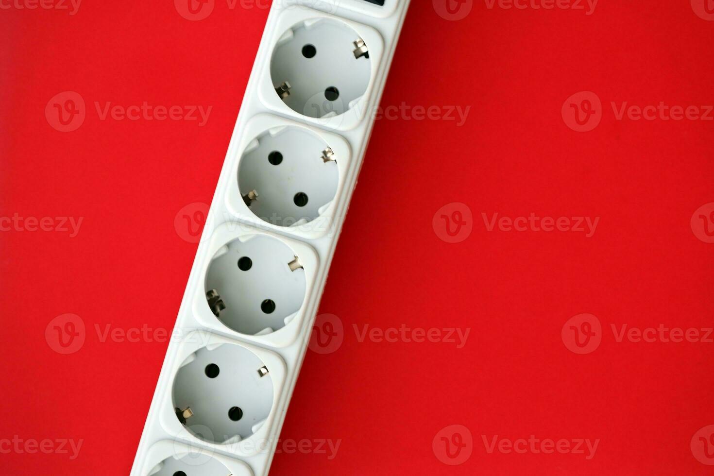 White electrical multi plug extender with european socket on bright red background photo