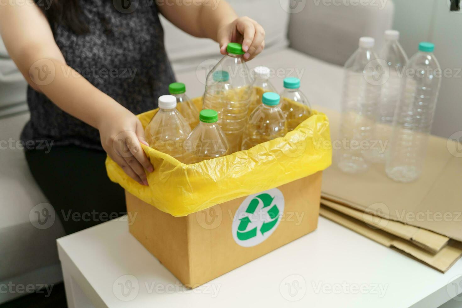 Home recycle eco green zero concept Woman throwing empty plastic bottle in recycling bin with yellow garbage bags at home. photo