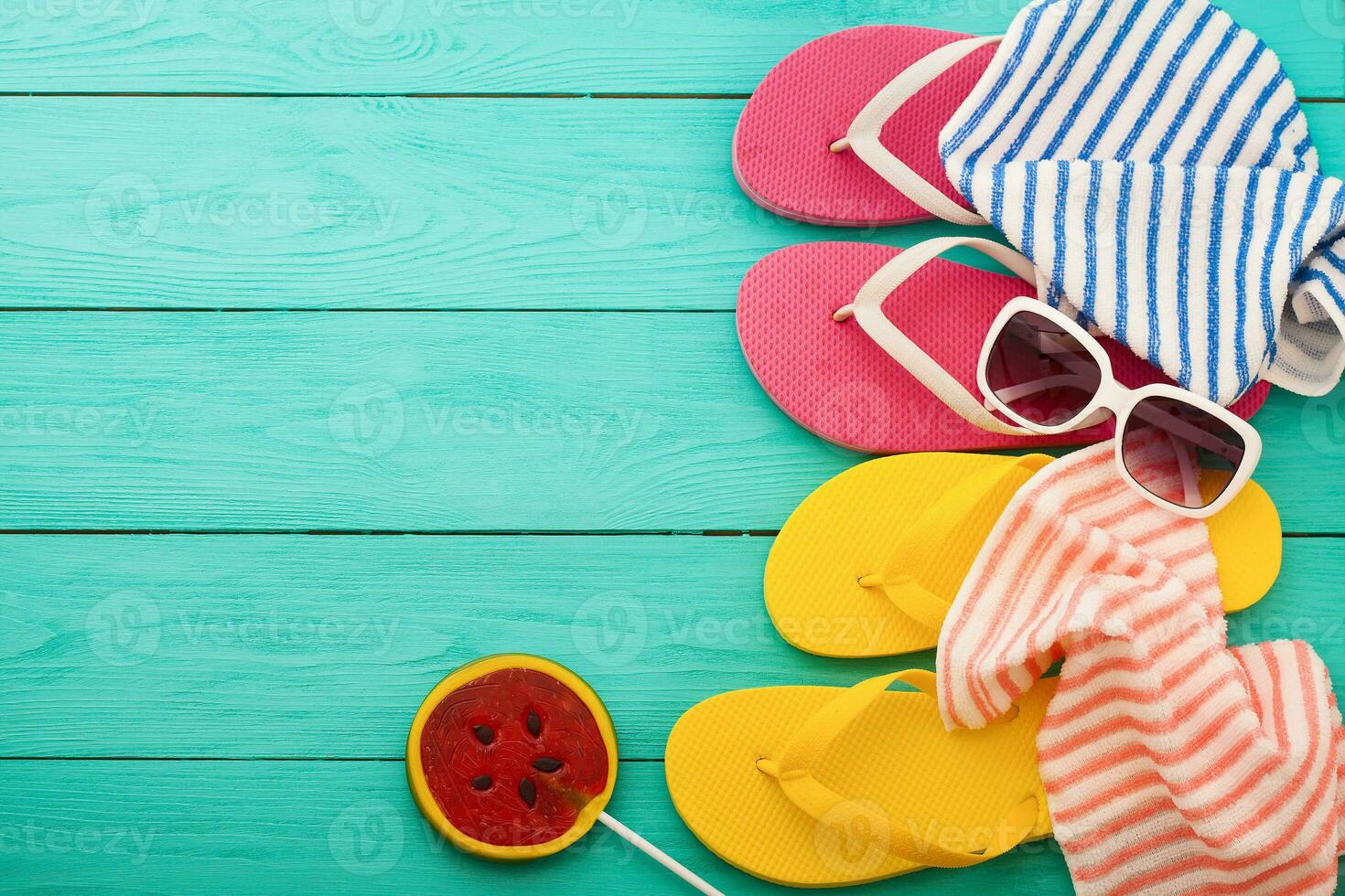 Pink flip flops with candy and copy space on blue wooden background. Top view photo