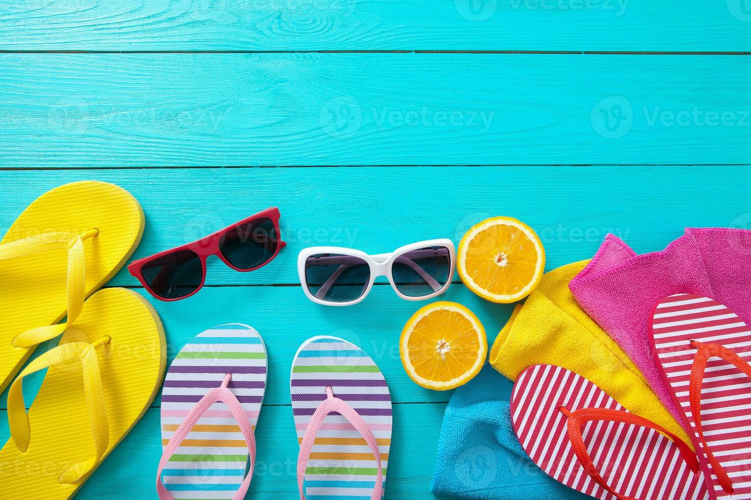 Summer accessories. Flip flops, sunglasses, towels and oranges on blue wooden background. Top view and copy space. photo