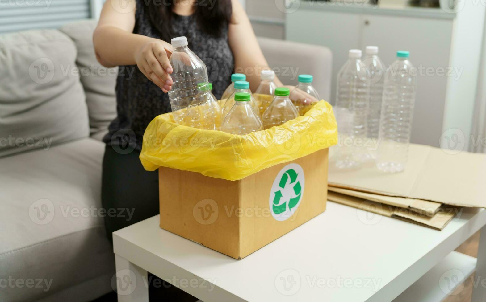 Home recycle eco green zero concept Woman throwing empty plastic bottle in recycling bin with yellow garbage bags at home. photo