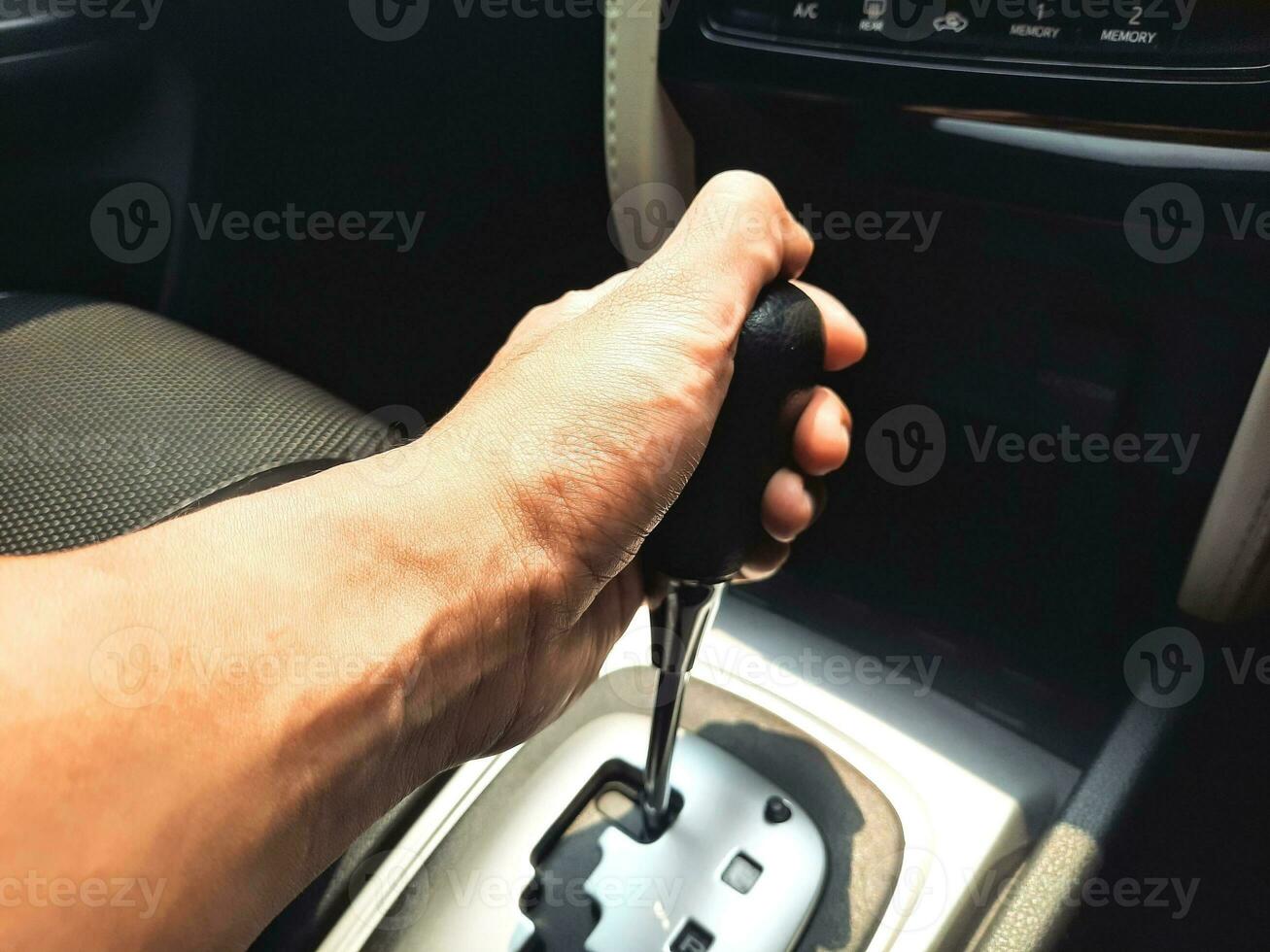 Man left hand holding the car gear lever. Car center console with automatic gearshift lever. photo