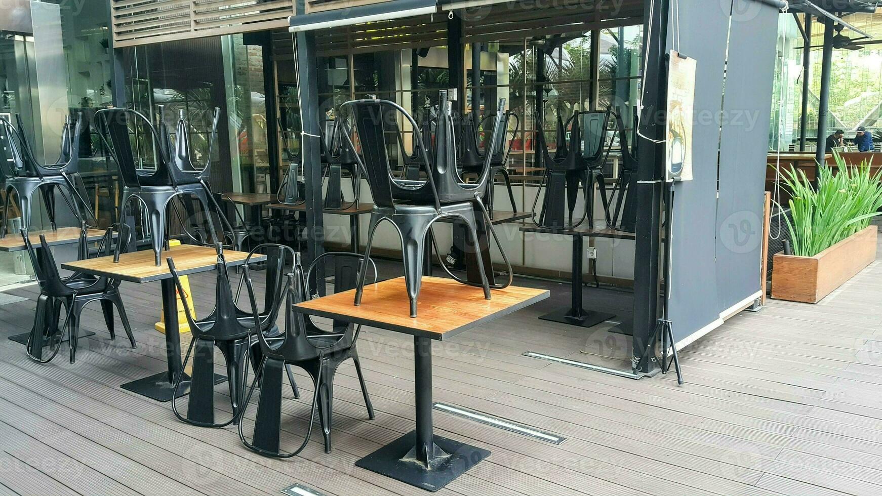 Empty table chairs in front of a restaurant. Empty wooden chairs and tables in front of the cafe. selective focus. photo