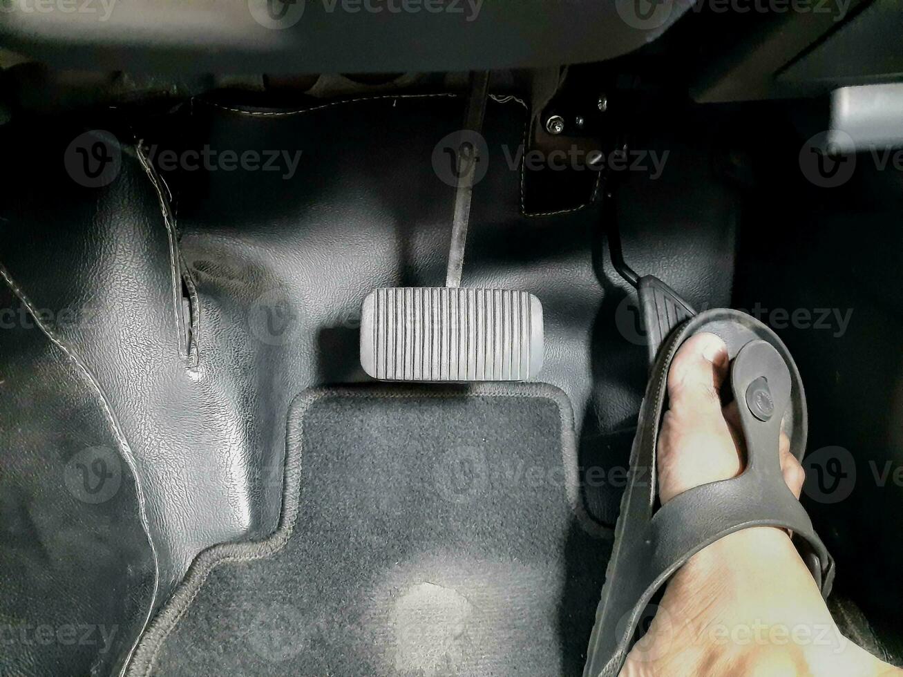 Close up images of man driving car by pushing accelerator and brake pedal with right foot with slippers photo