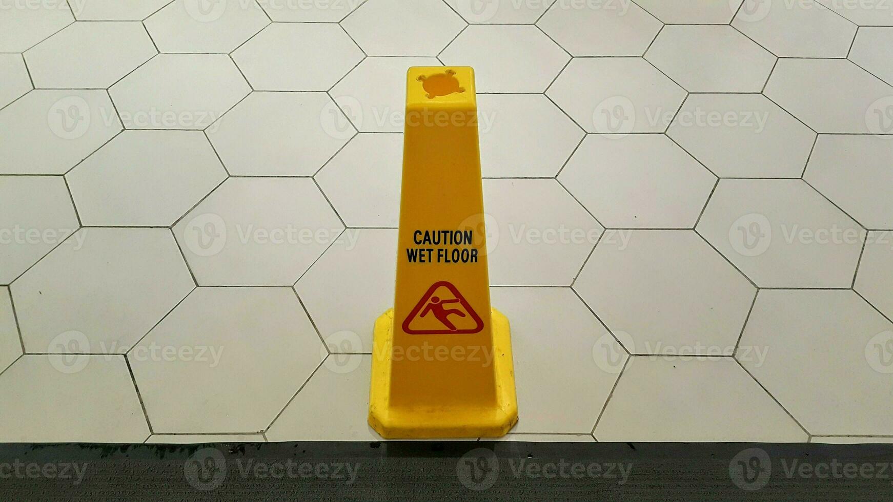 Yellow Caution slippery wet floor sign. Slippery sign on wet floor in a building. photo