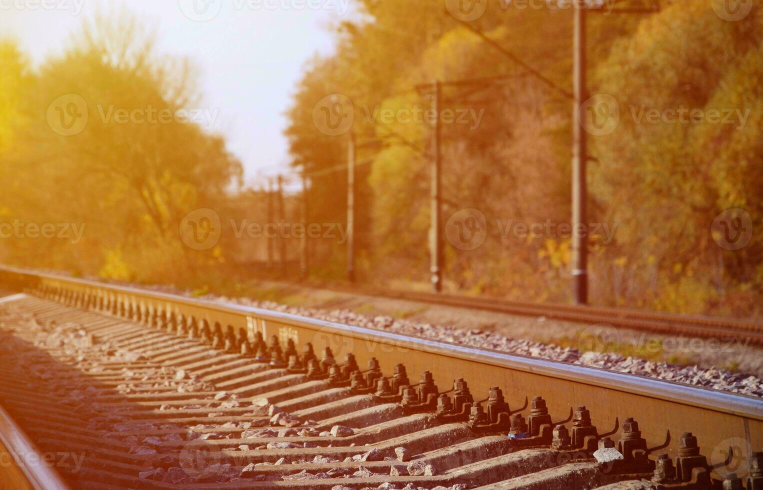 Autumn industrial landscape. Railway receding into the distance among green and yellow autumn trees photo