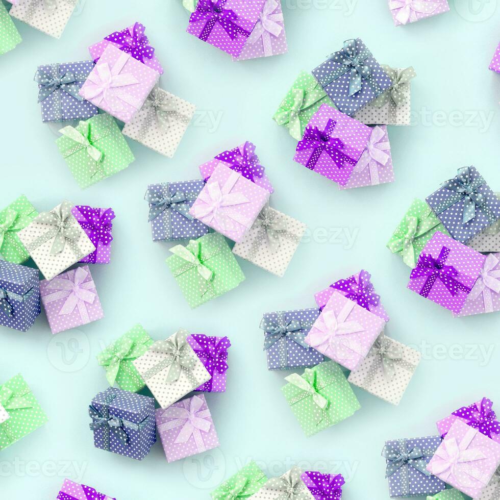 Piles of a small colored gift boxes with ribbons lies on a violet background. Minimalism flat lay top view pattern photo