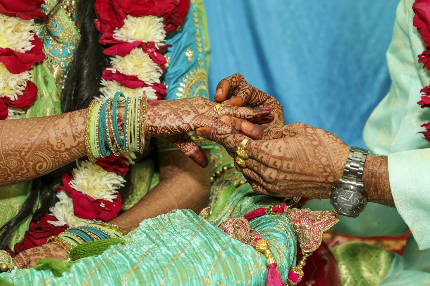 Indian groom wearing ring in bridal hand photo