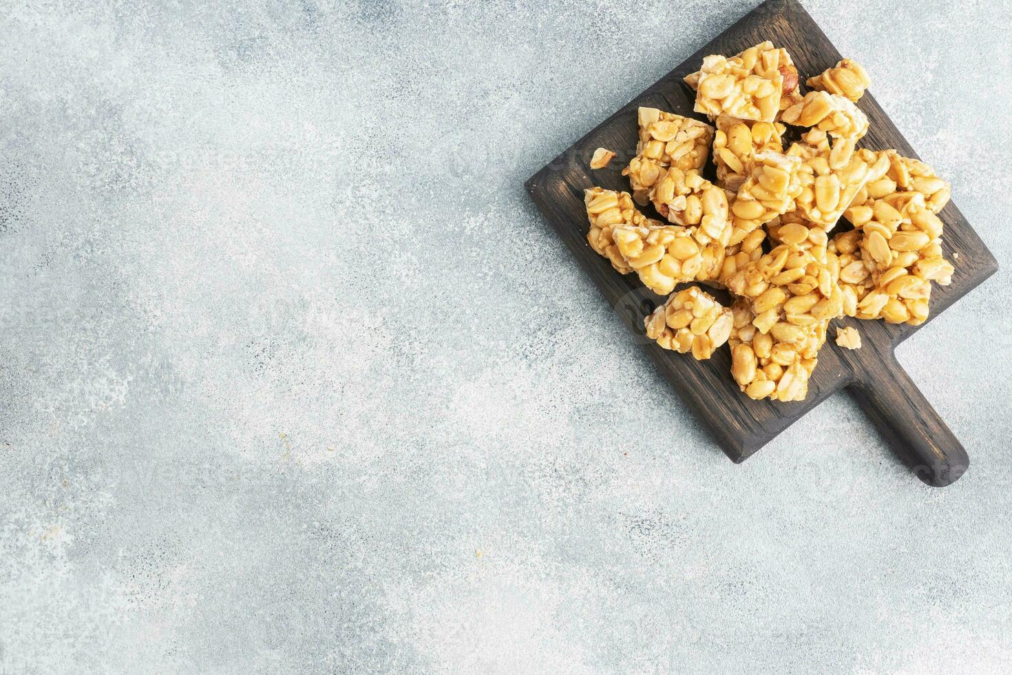 Peanuts in sugar glazed, oriental sweetness of brittle. Kozinaks are broken into pieces on a wooden Board, copy space. top view photo
