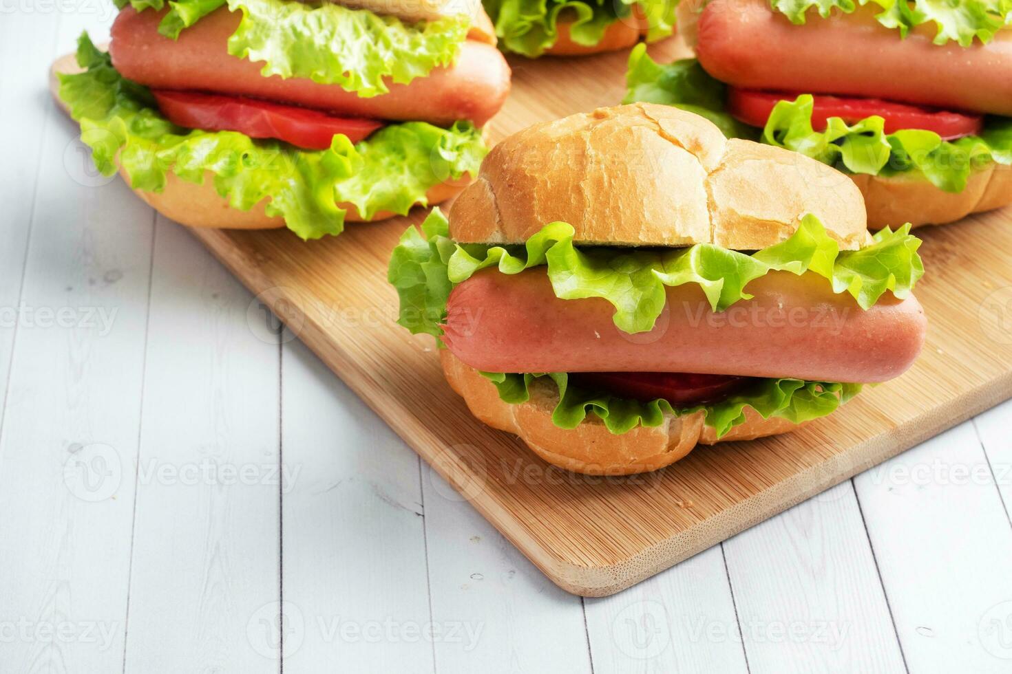 a few hot dogs on a wooden Board. Hot dog with lettuce tomato and sausage. Copy space. photo