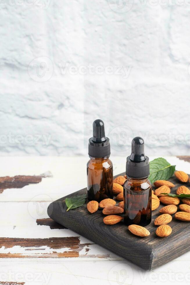 Almond essential oil in dark glass bubbles and fresh almond nuts. Aromatherapy oil natural organic cosmetic. photo