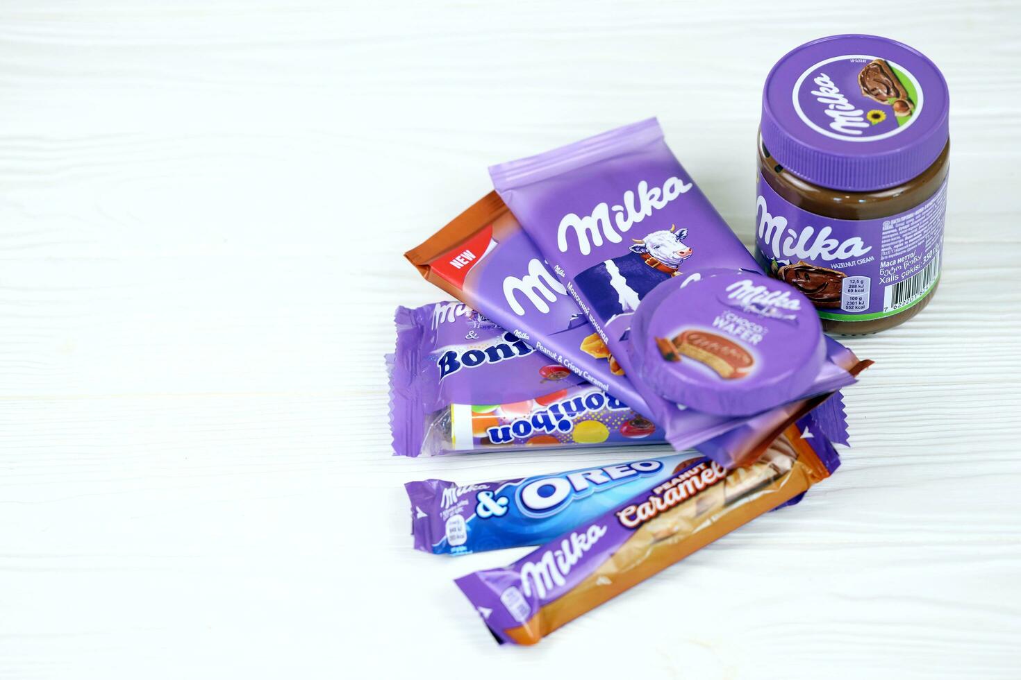 kharkov, ucrania - 2 de julio de 2021 productos de chocolate milka con diseño de envoltura de color lila clásico en mesa blanca foto