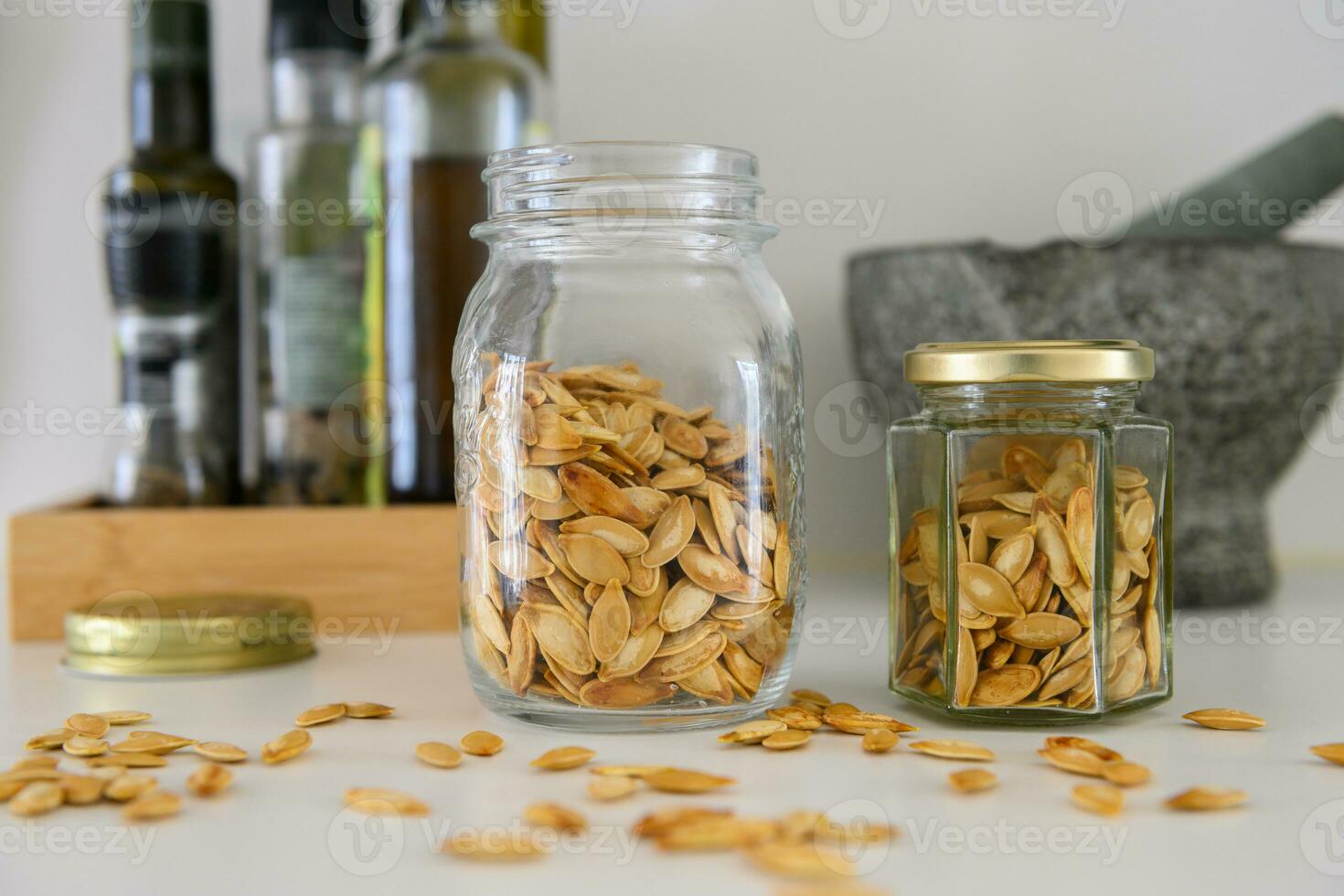 Two jars with pumpkin seeds on a kitchen table photo