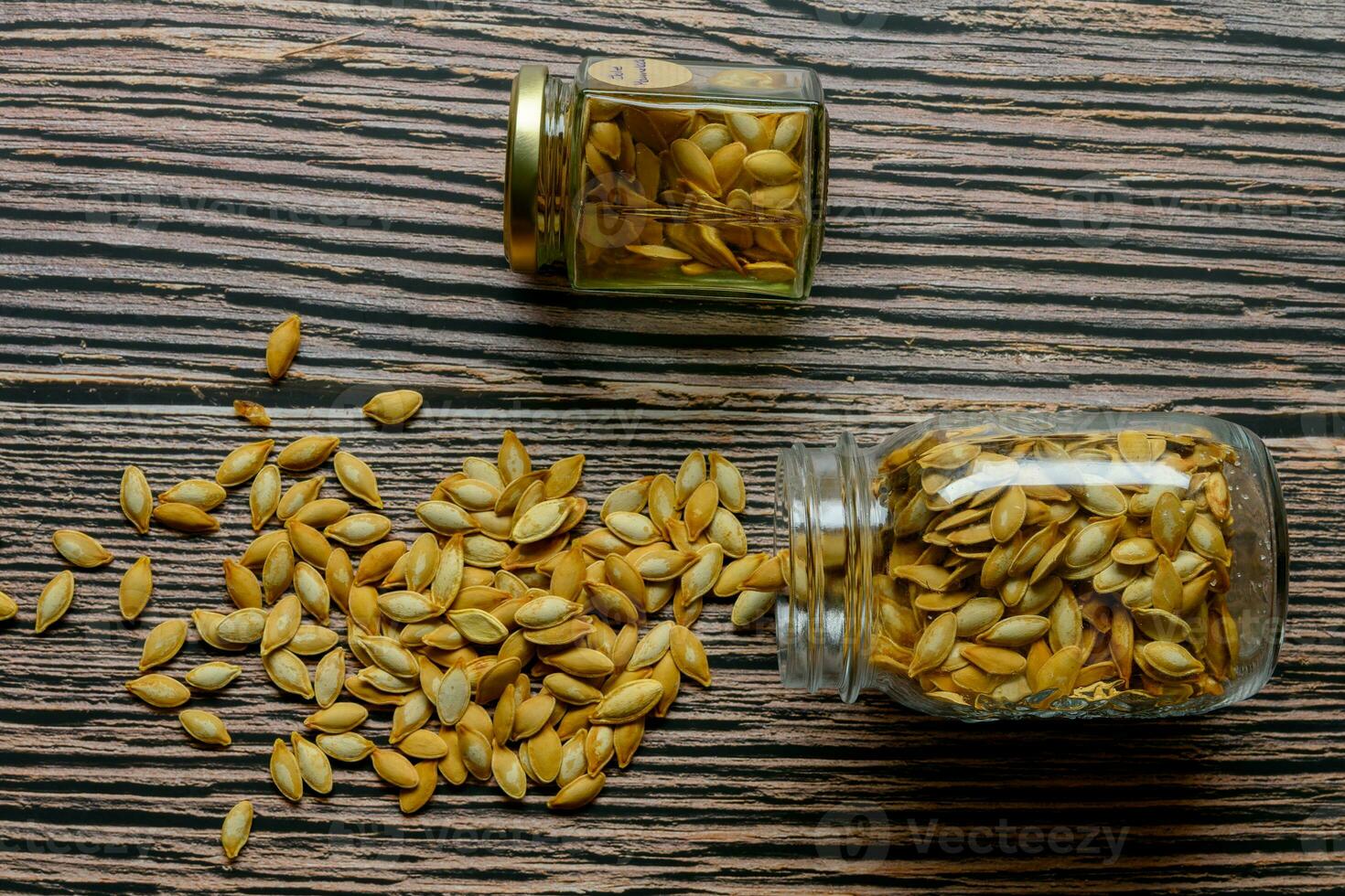 Two jars with pumpkin seeds on a rustic table photo