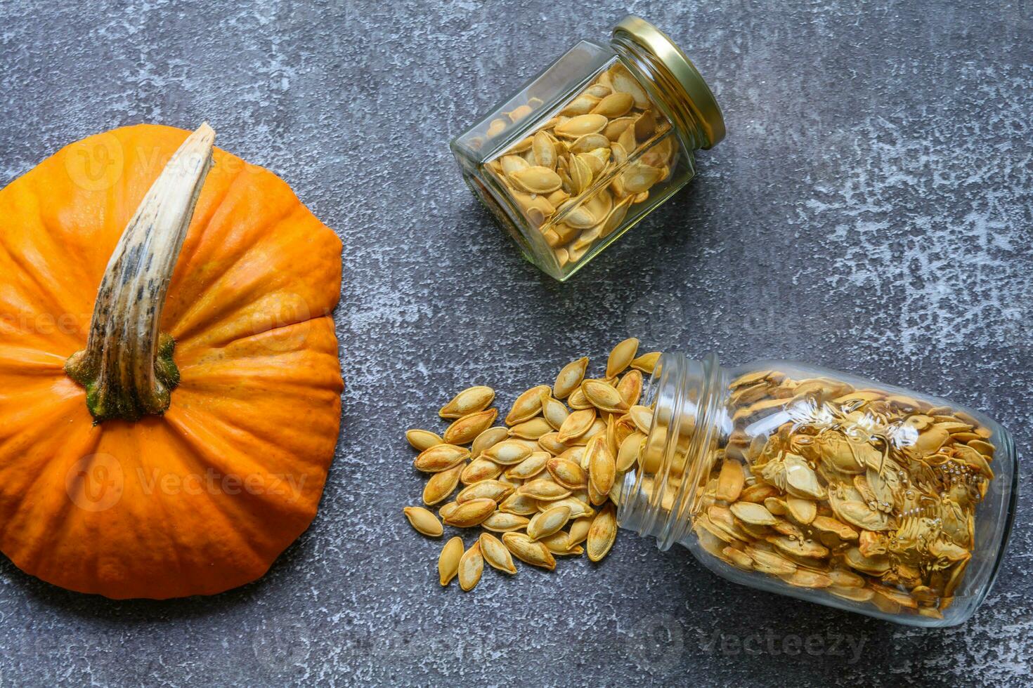 Two jars with pumpkin seeds on a rustic table photo