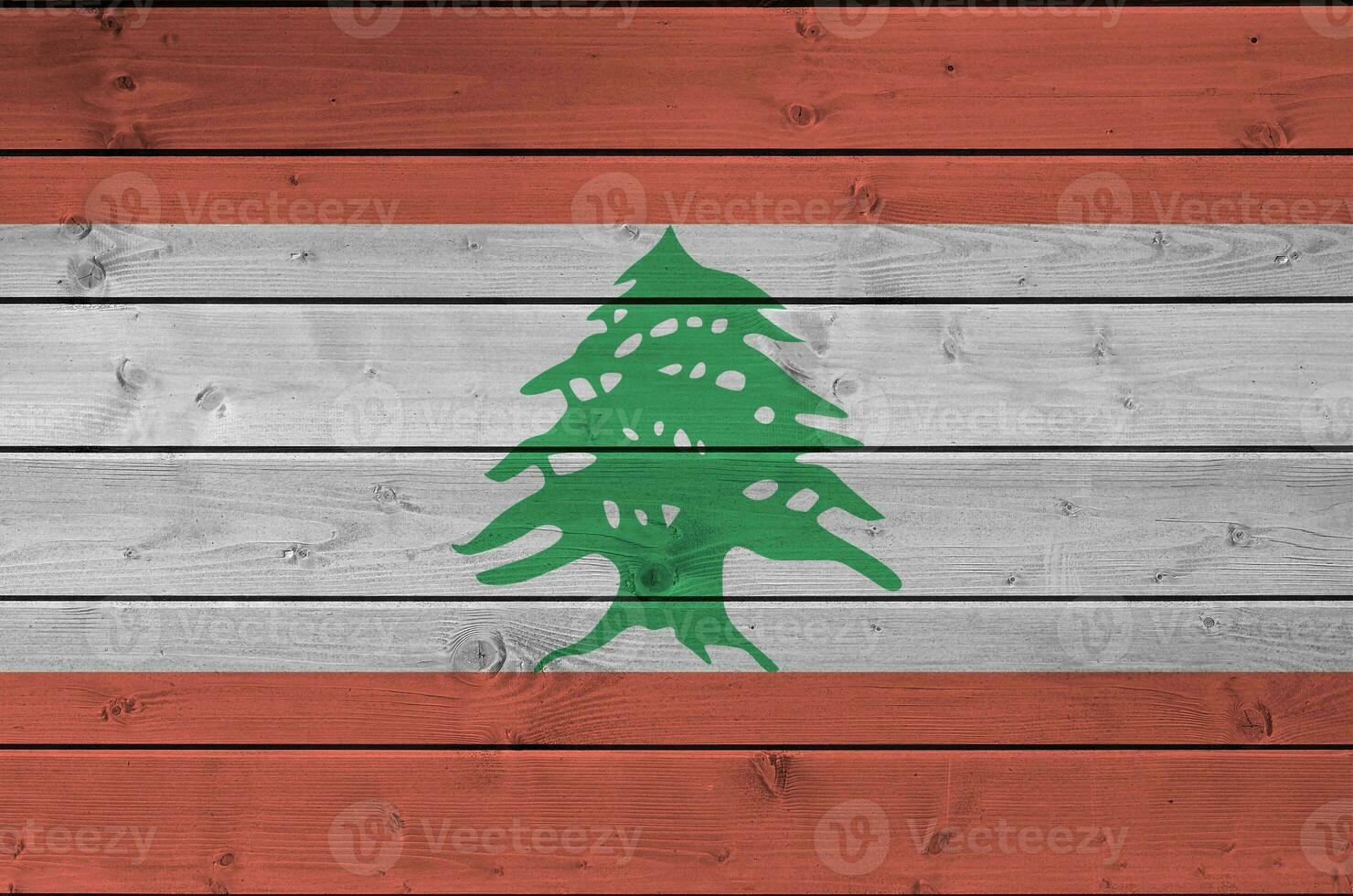 Lebanon flag depicted in bright paint colors on old wooden wall. Textured banner on rough background photo