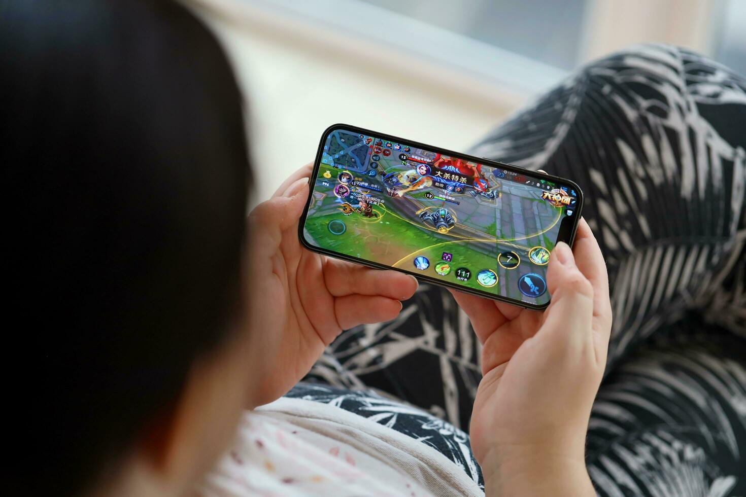 Honor of Kings mobile iOS game on iPhone 15 smartphone screen in female hands during mobile gameplay photo