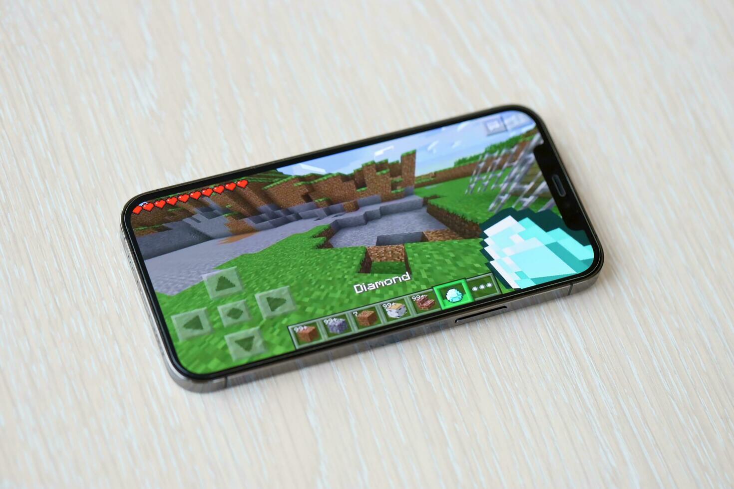 Minecraft mobile iOS game on iPhone 15 smartphone screen on wooden table during mobile gameplay photo