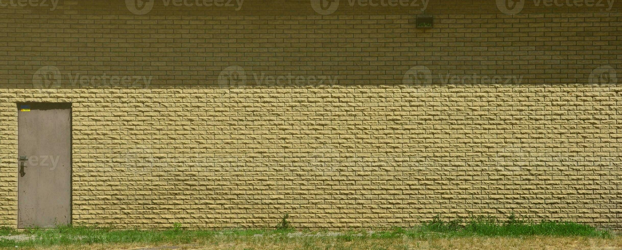 Texture of brick wall from relief stones under bright sunlight with metal door photo