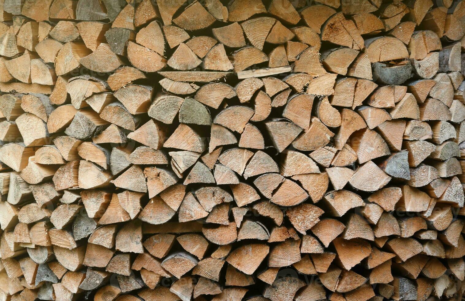 Firewood stacked near the wooden wall of old hut. Many chopped logs of firewood photo
