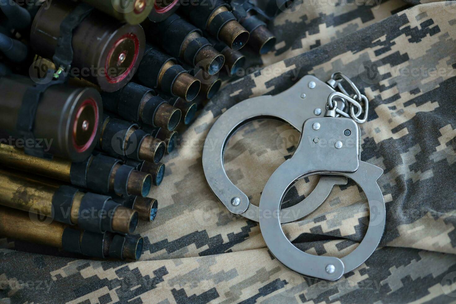 Ukrainian army machine gun belt shells and handcuffs on military uniform. Concept of bribery and war crimes photo