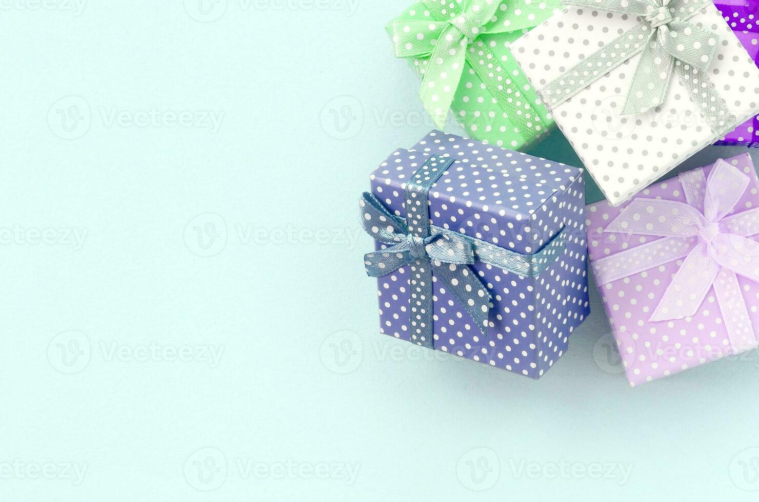 Pile of a small colored gift boxes with ribbons lies on a violet background. Minimalism flat lay top view photo