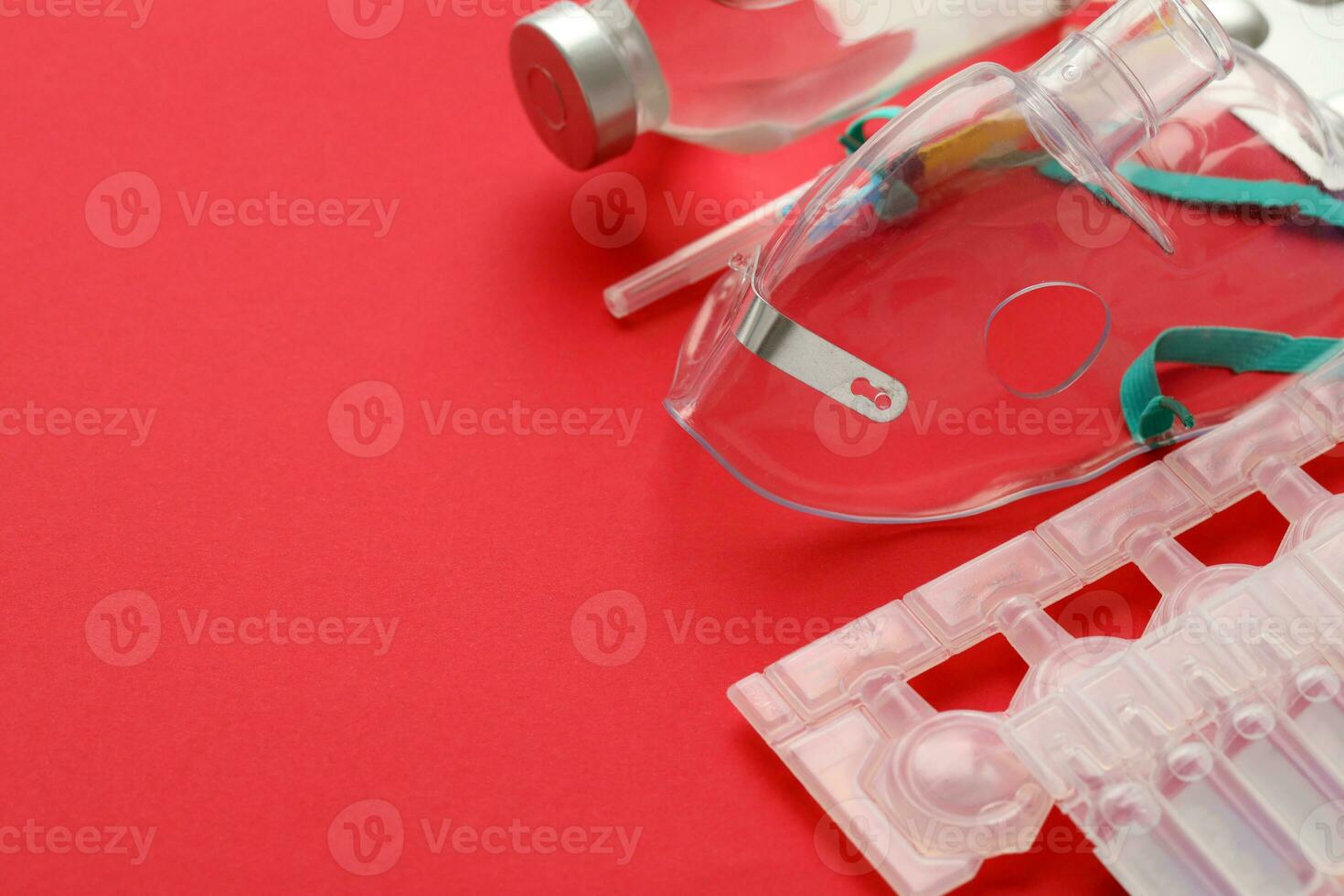 Coronavirus treatment concept. A medical face mask nebulizer for treatment of respiratory tract and packs of ampoules flat layed on red background photo
