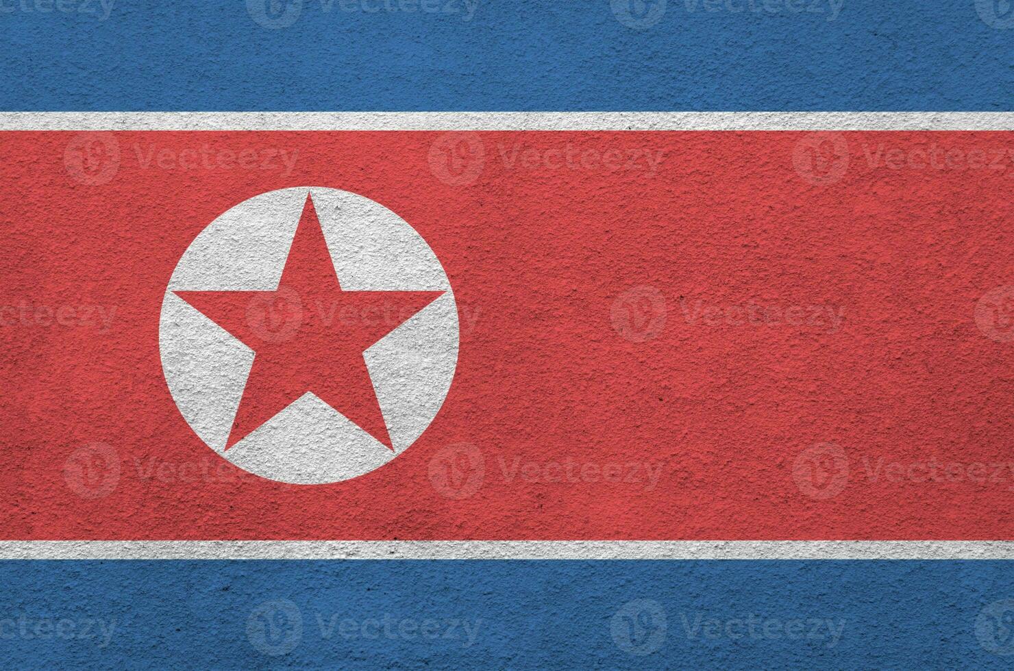 North Korea flag depicted in bright paint colors on old relief plastering wall. Textured banner on rough background photo