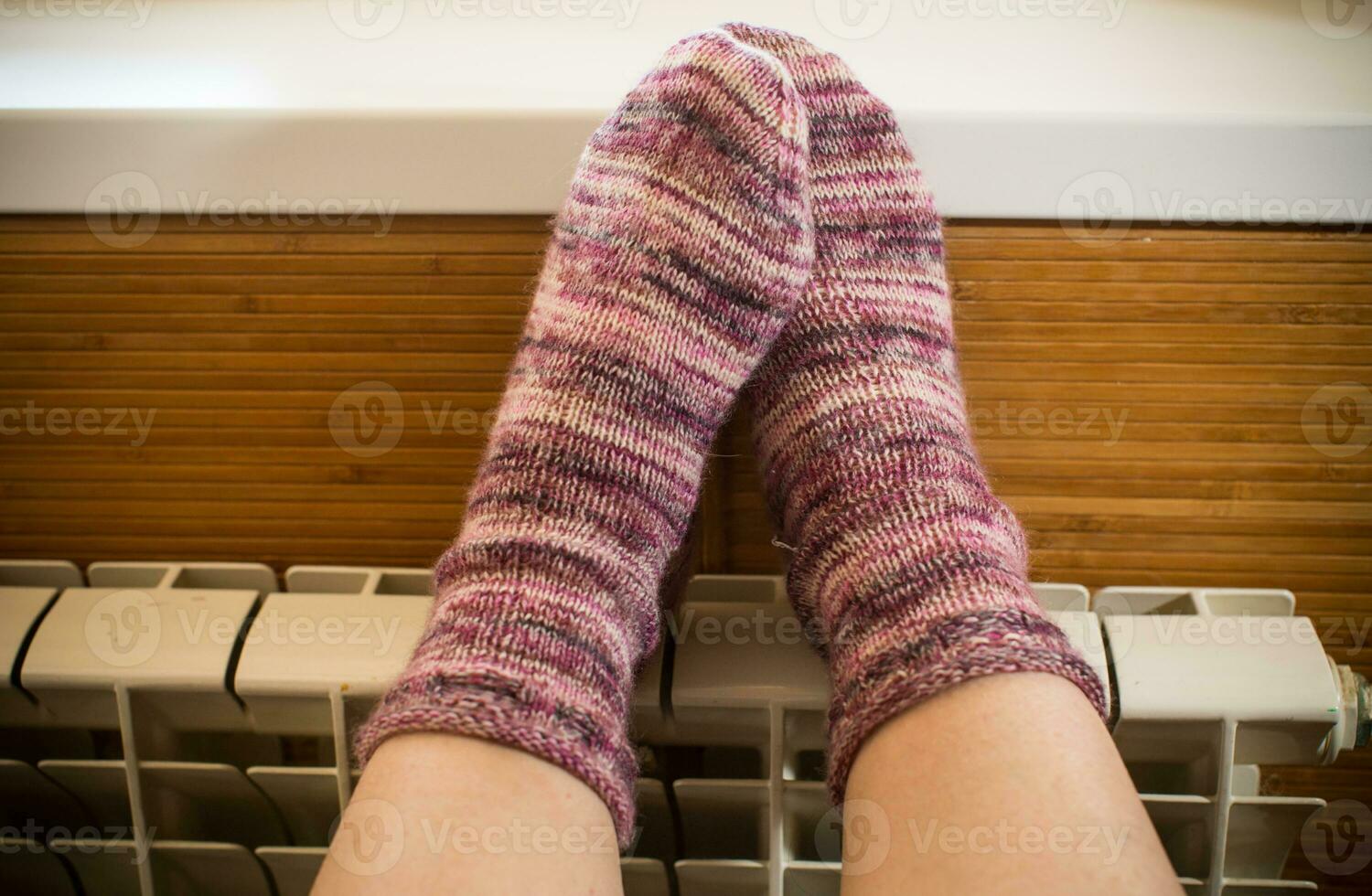 Feet in warm winter socks warm up on the radiator. photo